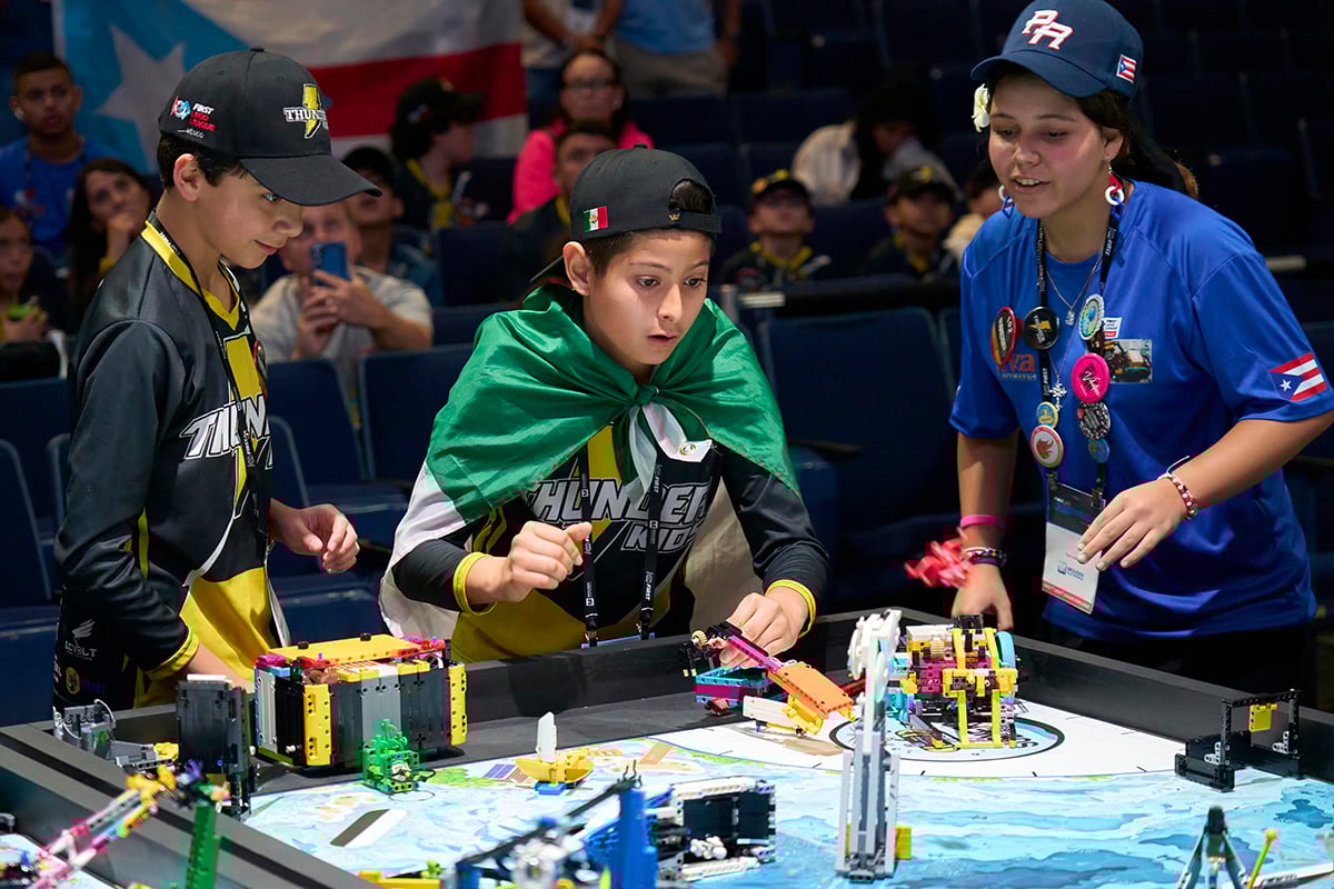 Three FIRST LEGO League students cheering on their robot at FIRST Championship.